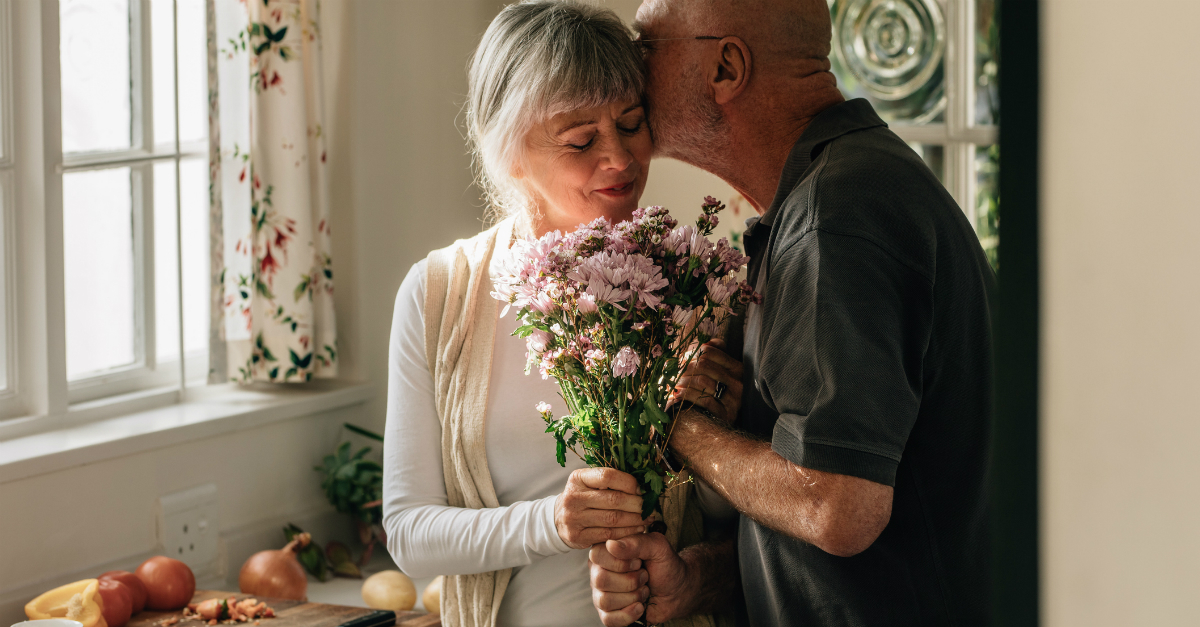 9228-senior-man-kissing-wife-holding-flowers-by-ki.jpg