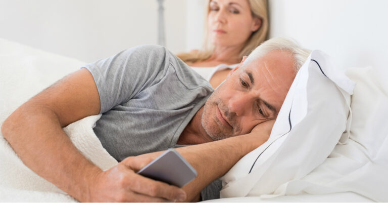 9108-senior-husband-in-bed-with-wife-ignoring-cell.jpg