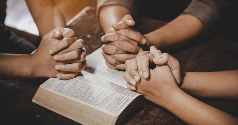 Group-of-People-Praying-Together-over-Open-Bible.png