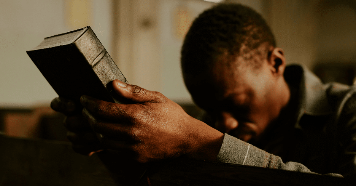 Man-Holding-a-Bible-and-Bowing-His-Head-in-Prayer.png